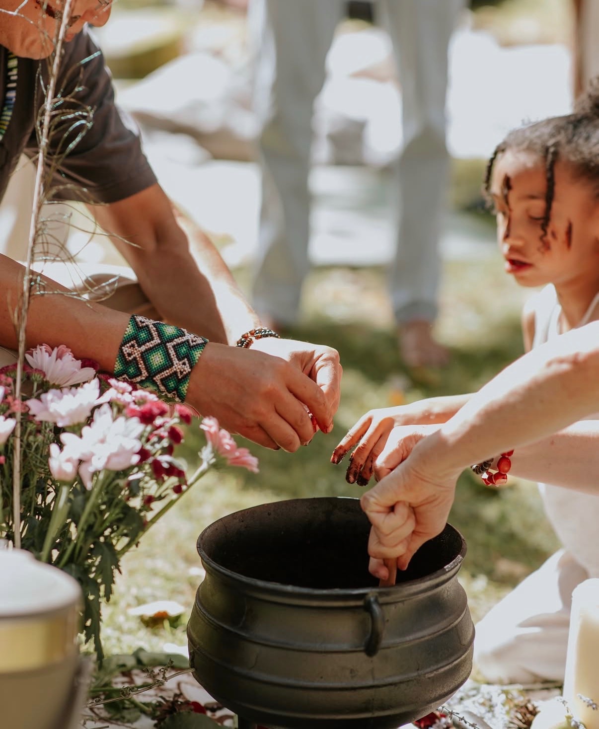 Guests adding flowers to the cacao pot at a group cacao ceremony