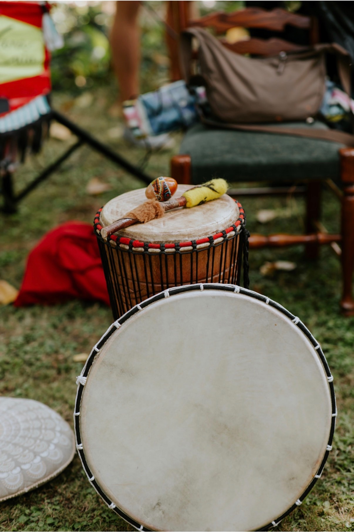 A frame drum and djembe with rattles laid on the grass before a cacao ceremony