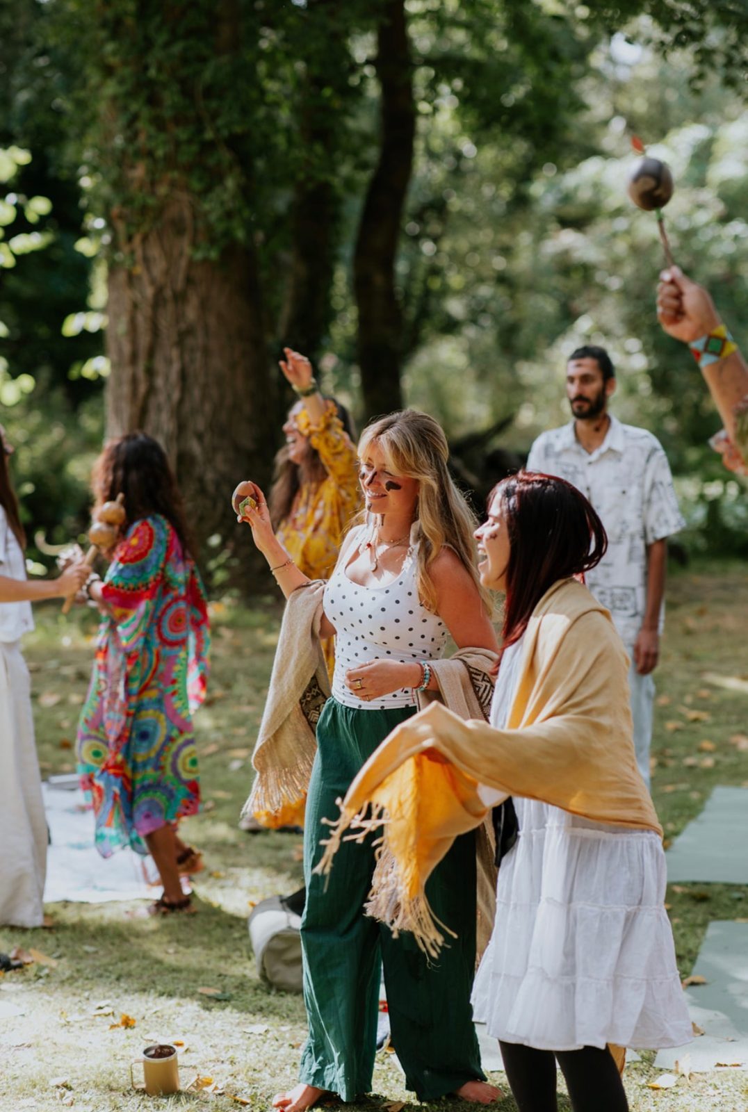 Women dancing with rattles and shawls at an outdoor ceremony