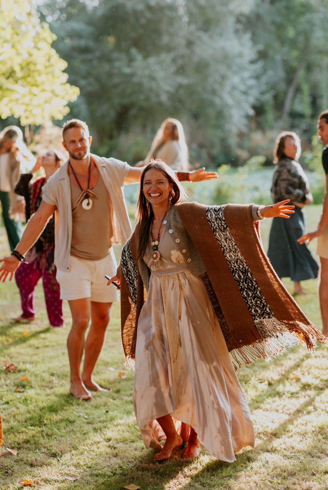 Smiling woman dancing barefoot on the grass at an outdoor group ceremony