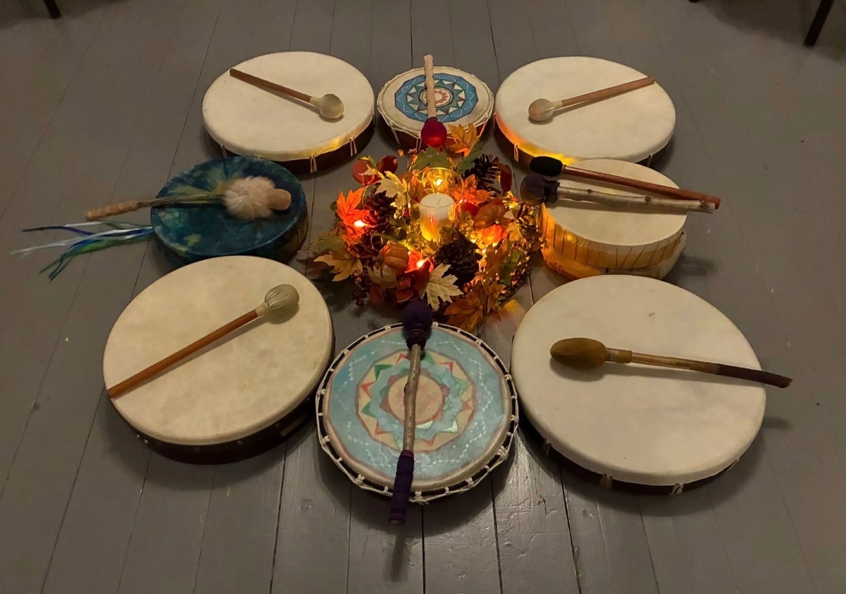 Circle of frame drums around an autumn-leaf centrepiece for the women's drum and cacao ceremony